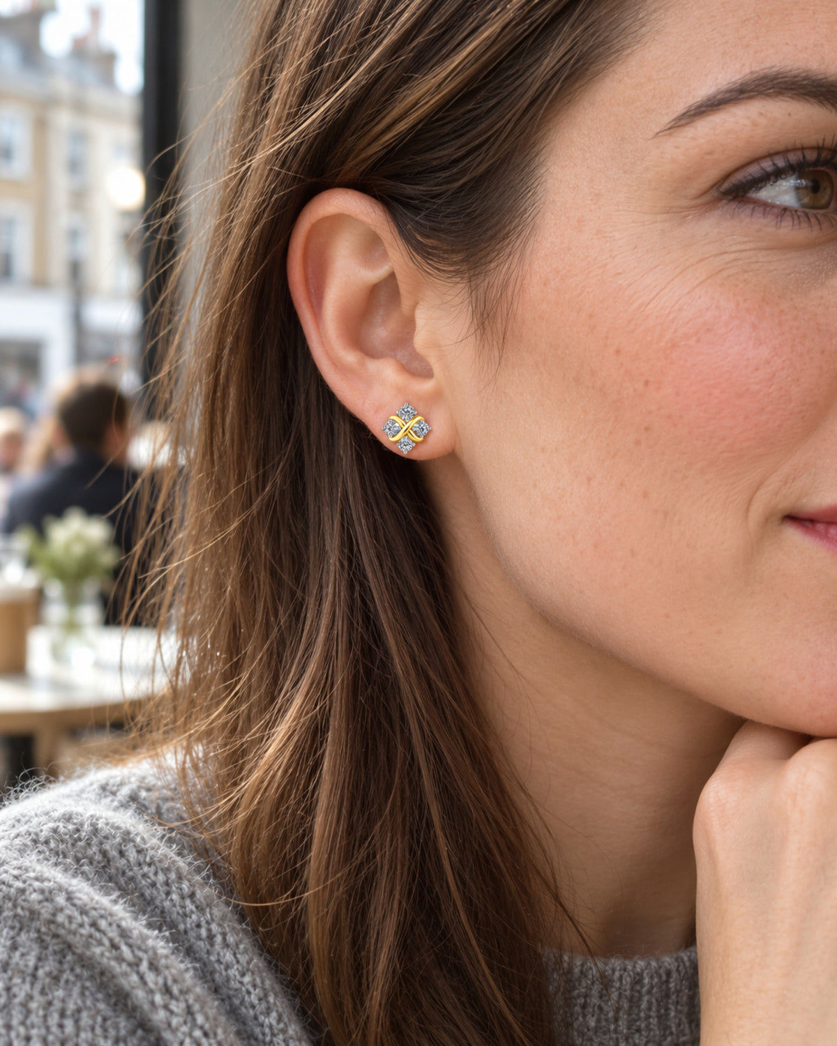 British woman wearing crossover moissanite stud earrings in a café