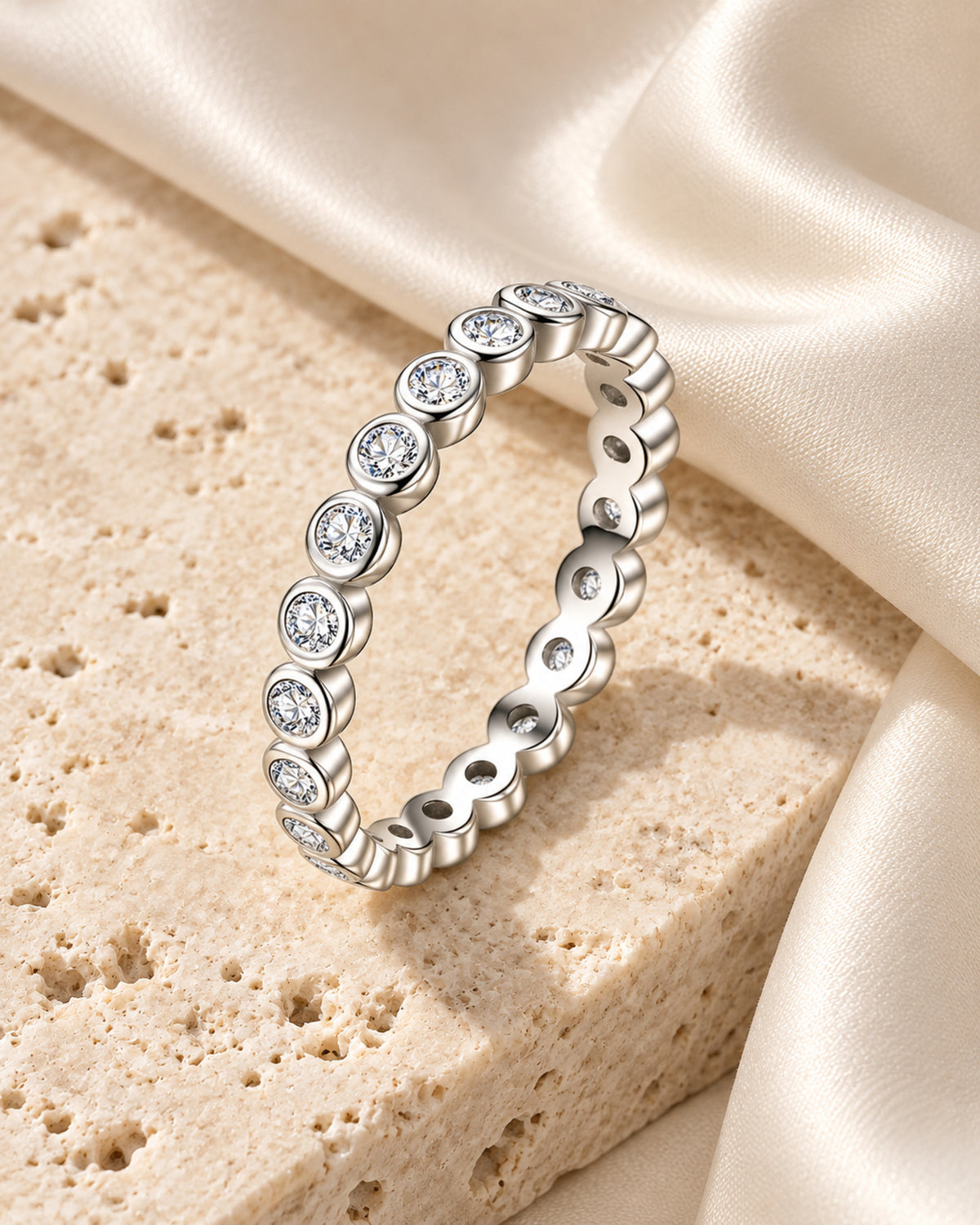Bezel-set moissanite eternity ring on ivory travertine