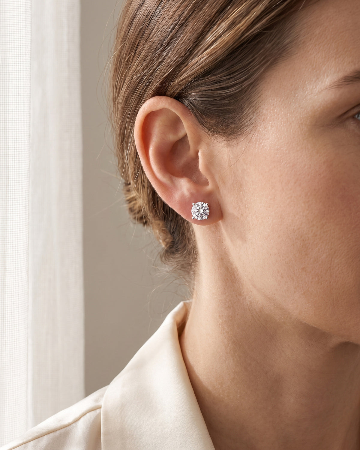 Woman wearing a silver-tone round moissanite stud earring